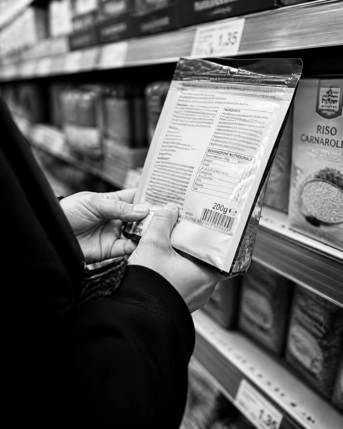 A shopper reading the ingredients label on a packet in a supermarket aisle